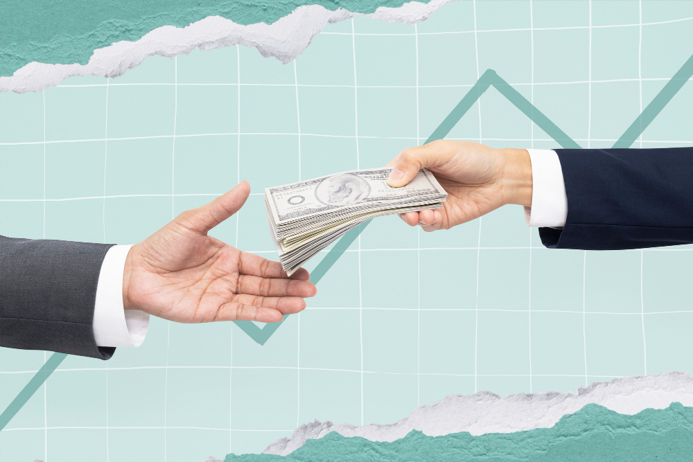 Illustration of one hand passing a stack of cash to another hand, both in business attire, symbolizing a financial transaction or investment. The background features a rising line graph, indicating financial growth or success. The image conveys themes of business dealings, investment, and monetary exchange.