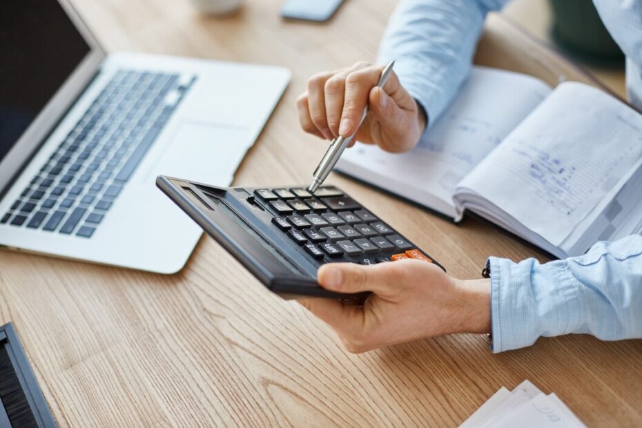 cropped-view-professional-serious-finance-manager-holding-calculator-hands-checking-company-month-s-profits